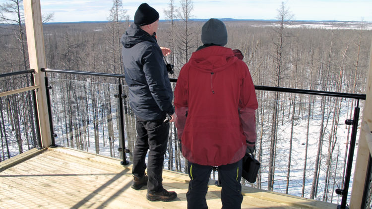 Två personer strå i ett utsiktstorn och blickar ut över ett snöigt landskap.